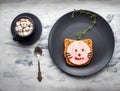 Funny sandwich with sausage under a cat`s face on a black plate and a cup of coffee with marshmallows and chocolate Royalty Free Stock Photo