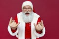 Funny Santa Claus wearing costume showing horns isolated on red background. Royalty Free Stock Photo