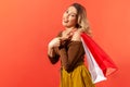 Funny satisfied woman showing tongue pointing finger at paper bags on her shoulder, bragging with successful shopping Royalty Free Stock Photo