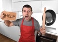 Funny scared man holding pan wearing apron at kitchen asking for help Royalty Free Stock Photo