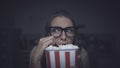 Woman watching a horror movie and eating popcorn