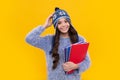 Funny school girl child student with book and warn hat, isolated yellow background. Learning and knowledge education