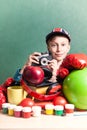 Funny schoolboy sitting at table with colorful school accessories