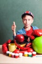 Funny schoolboy sitting at table with colorful school accessories Royalty Free Stock Photo