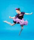 Funny schoolgirl jumping on blue background in studio