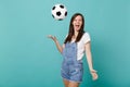 Funny screaming young girl football fan cheer up support favorite team throwing up soccer ball isolated on blue