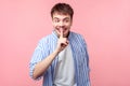 Funny secret, don`t tell anyone! Portrait of positive brown-haired man showing silence gesture. on pink background