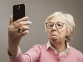 Funny senior lady taking selfies with toungue out