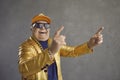 Funny senior man in golden jacket, baseball cap and chain necklace dancing and having fun Royalty Free Stock Photo