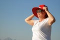 Funny senior woman wearing santa claus hat over sun hat on the sea beach, woman dancing and wishes a merry Christmas and happy new Royalty Free Stock Photo