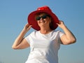 Funny senior woman wearing santa claus hat over sun hat on the sea beach, woman dancing and wishes a merry Christmas and happy new Royalty Free Stock Photo