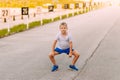 Funny seven-year-old boy in blue shorts and sneakers is on the pavement in the summer