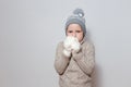 Funny seven-year-old boy in white knitted mittens and sweater on a white background