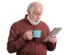 Funny shocked senior man with cup using tablet computer isolated on white