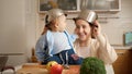 Funny shot of little baby boy with bowl on head looking at mothre with cooking pan on kitchen Royalty Free Stock Photo