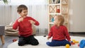 Funny shot of two little brother dancing on carpet in living room. Concept of child education, baby development, family having fun