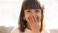 Funny shy girl laughing covering mouth with hand, headshot portrait Royalty Free Stock Photo