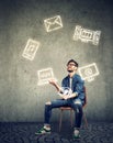 Funny skillful man sitting on chair and juggling with electronic devices icons Royalty Free Stock Photo