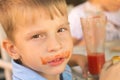 Funny small boy drinking tomato juice in cafe Royalty Free Stock Photo