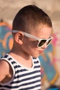 Funny small boy wearing sunglasses and sailor shirt on graffiti background Royalty Free Stock Photo