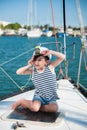 Funny small captain kid on yacht boat board in summer sea port