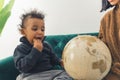 Funny small child eating cookie while looking th the globe