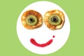 Funny smiley face. Smiley funny face pancakes, decorated with kiwi fruit, currants and jam on the white plate, green background.