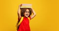 Funny smiling Black child school girl with glasses hold books on her head Royalty Free Stock Photo