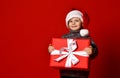 Funny smiling joyful child boy in Santa red hat holding Christmas gift present in hands Royalty Free Stock Photo