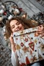 Funny smiling joyful child girl holds a Christmas present in his hand on a background of Christmas decorations and a Royalty Free Stock Photo