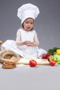 Funny Smiling Little Caucasian Girl In Cook Uniform Making a Mix of Flour, Eggs and Vegetables In Studio Royalty Free Stock Photo