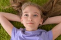 Portrait of funny smiling little girl lying on green carpet Royalty Free Stock Photo