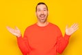 Funny smiling man in red sweater showing palms up, unexpected surprise gesture isolated over yellow background Royalty Free Stock Photo