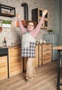 Funny smiling man wearing pinafore with hands up on the kitchen