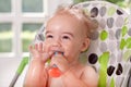 Funny smiling ragged baby holding spoon in mouth