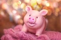 Funny smiling rubber pig toy stands in a woolen openwork scarf against a background of yellow bokeh