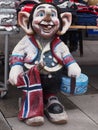 Funny smiling troll statue toothless holding Norwegian flag and gift box at the entrance of a gift shop in Norway