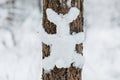 Funny snow figure on tree in winter forest