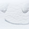 Funny snow smile painted on the white snow background, happy winter concept Royalty Free Stock Photo