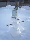 Funny snowman with a carrot nose, with eyes made of coals and hands in the form of sticks. Rural street. Christmas photography