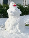 Funny snowman with corncob nose, stone eyes, funny white decorative ribbon hair and red mask over mouth