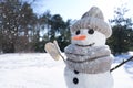 Funny snowman with hat and scarf in winter forest on sunny day, closeup. Space for text Royalty Free Stock Photo