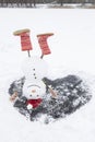 funny snowman in red boots stands upside down on a frozen snowy lake