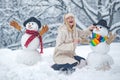 Funny snowmen. Happy smiling girl make snowman on sunny winter day. People in snow. Snowman. Beauty Winter Girl with Royalty Free Stock Photo