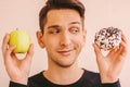 Funny sports man deciding to eat unhealthy sweet snack Royalty Free Stock Photo