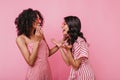 Funny story made two friends laugh heartily. Portrait of girls in pink striped outfits who are havi Royalty Free Stock Photo