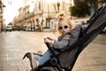 Funny,stylish blonde caucasian baby toddler girl with ponytail,sunglasses sit at stroller looking at camera, at Isticlal Royalty Free Stock Photo