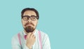Funny and stylish male nerd thinking or making decisions on light blue background. Royalty Free Stock Photo