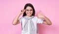 Cute fashionable emotional girl with glasses in a basic T-shirt on a pink background