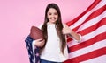 The American sport football.USA. Young beautiful girl in a white T-shirt with the American flag, on a pink background Royalty Free Stock Photo